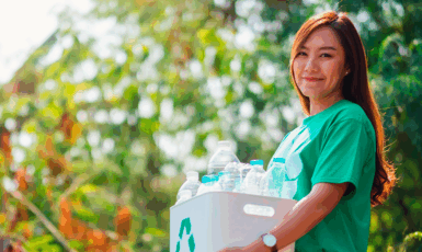 Mulher carregando caixa com materiais recicláveis.