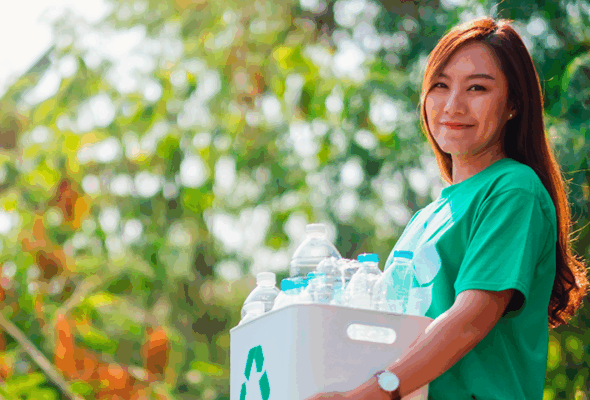 Mulher carregando caixa com materiais recicláveis.