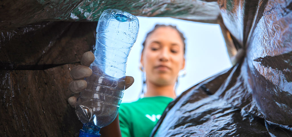 Mulher reciclando uma garrafa plástica.
